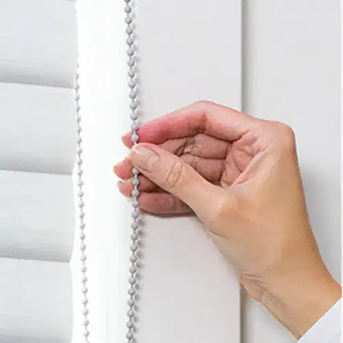 Hand using the continuous cord loop on Hunter Douglas Sonnette cellular roller shades