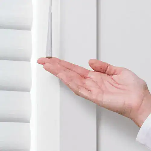 Hand pressing the SoftTouch motorization button on Hunter Douglas Sonnette shades