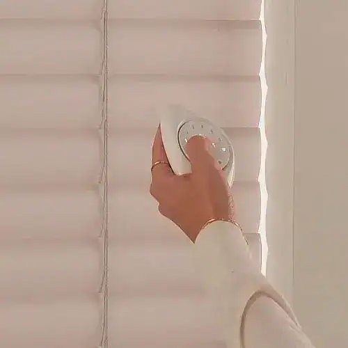 Hand using a PowerView remote to operate Hunter Douglas Aria fabric blinds