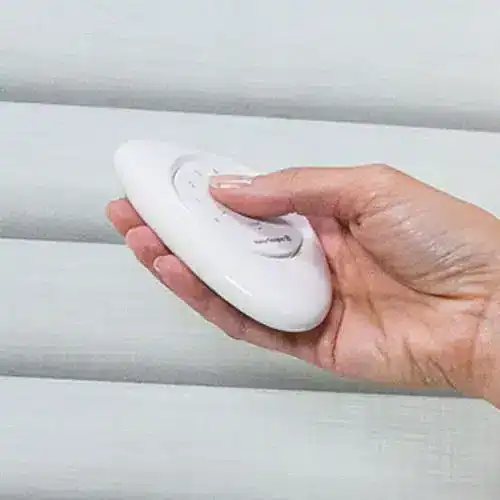 Hand using a PowerView remote to operate Hunter Douglas Sonnette cellular roller shades
