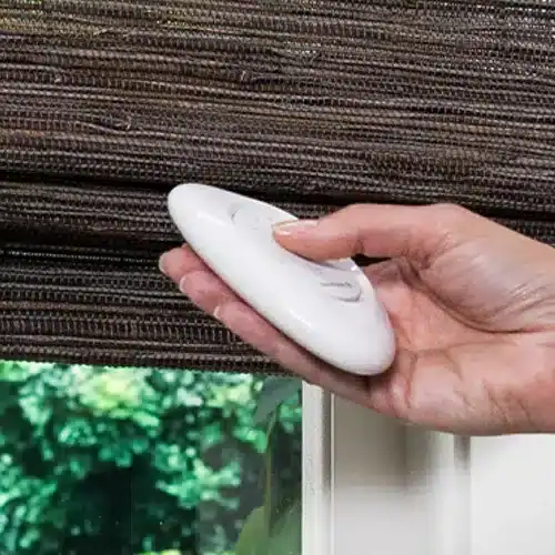Hand holding a PowerView Pebble remote for Hunter Douglas Provenance woven wood shades