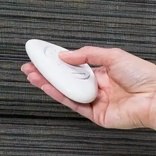 Hand using a PowerView remote to operate Hunter Douglas Alustra Woven Textures Roman Shades