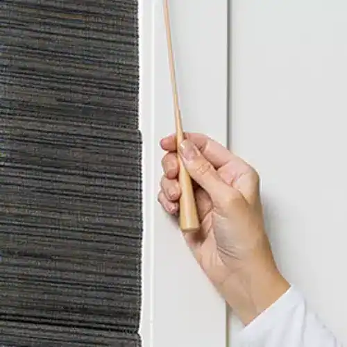 Hand using the UltraGlide wand on Hunter Douglas Alustra Woven Textures Roman Shades