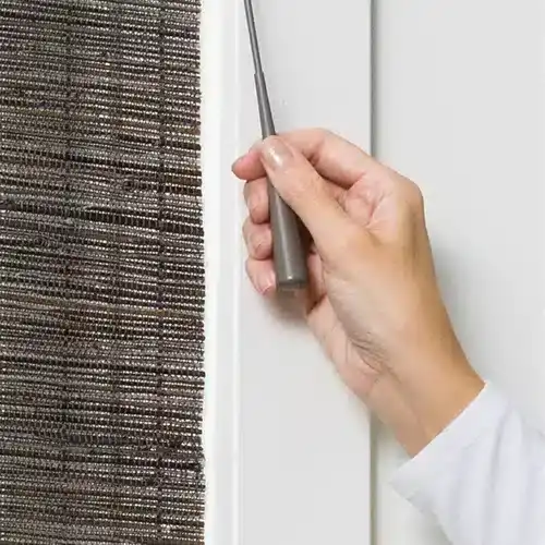 Hand using the UltraGlide wand on Hunter Douglas Provenance woven wood shades