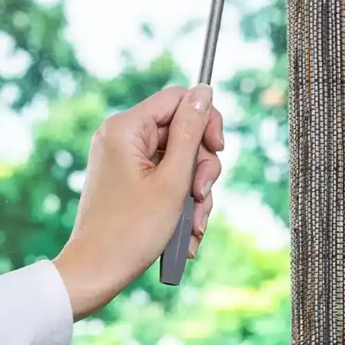 Hand using the wand control on Hunter Douglas Provenance woven wood shades