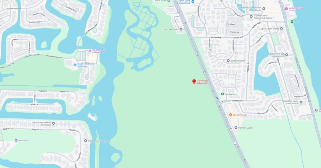 A scenic view of a lake with surrounding residential neighborhoods and green spaces during sunset, showcasing natural beauty and community layout.