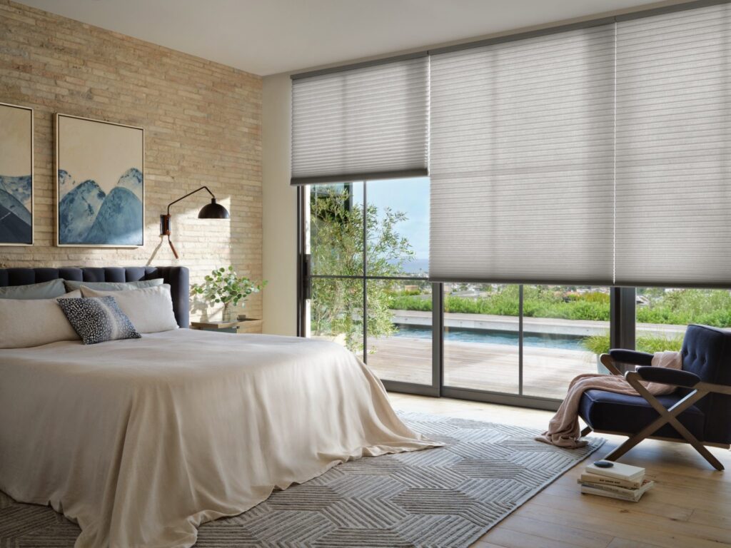 Applause® Honeycomb Shades in Kinship™ with PowerView® Automation in a bedroom with a pool view
