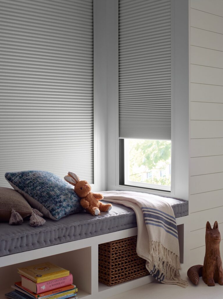 Close-up of Duette® Honeycomb Shades with the LightLock® system above a window seat