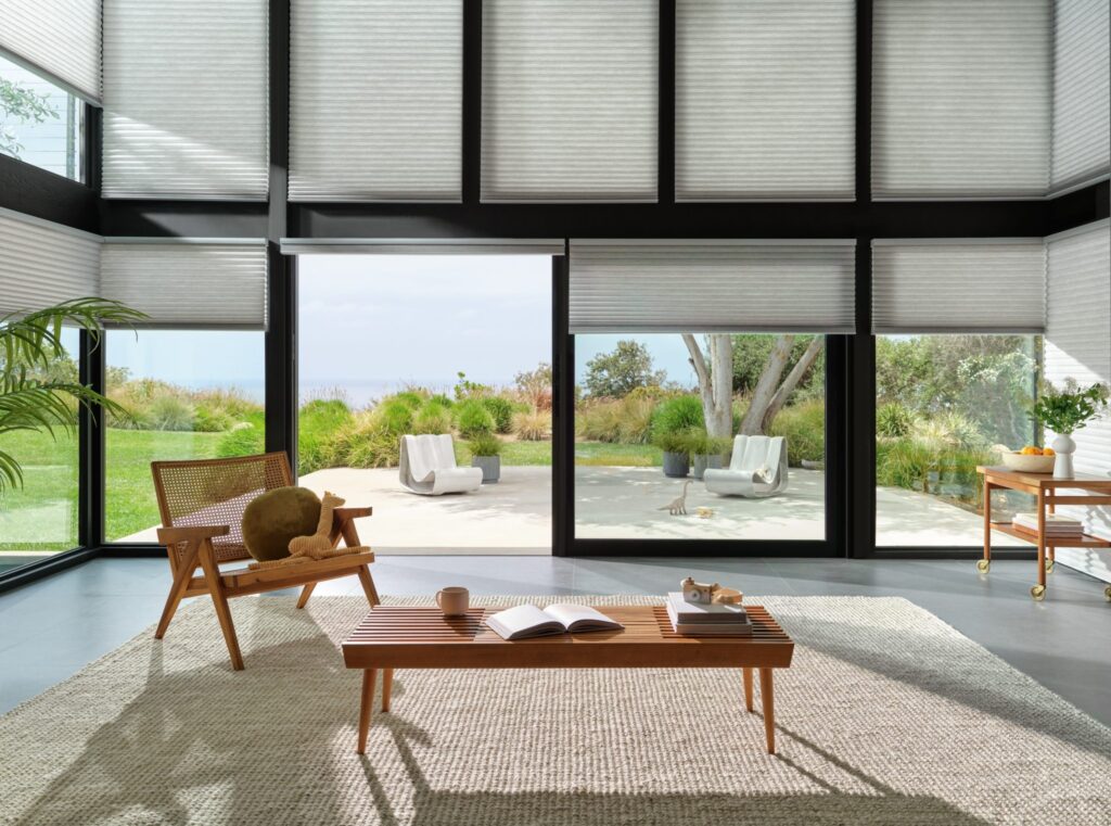 Duette® Honeycomb Shades in Thea™ with PowerView® Automation in a living room with a garden view