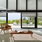 Duette® Honeycomb Shades in Thea™ with PowerView® Automation in a living room with a garden view