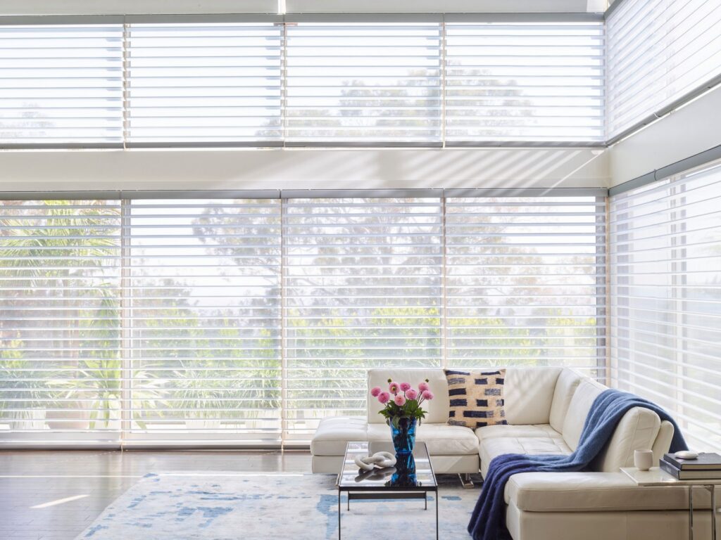 Silhouette® Window Shadings on a wall of windows in a living room with a white sectional
