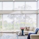 Silhouette® Window Shadings on a wall of windows in a living room with a white sectional