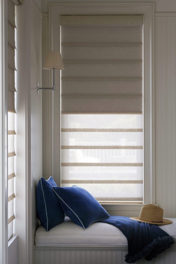 Close-up of Vignette® Modern Roman Shades in Leela™ with Duolite® and PowerView® Automation over a window seat